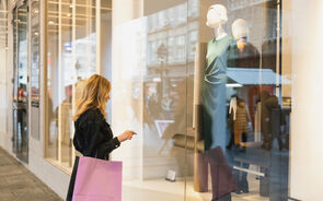 Turista observa montra em Portugal, refletindo tendências de consumo