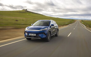 Um carro azul da BYD circula numa estrada rural