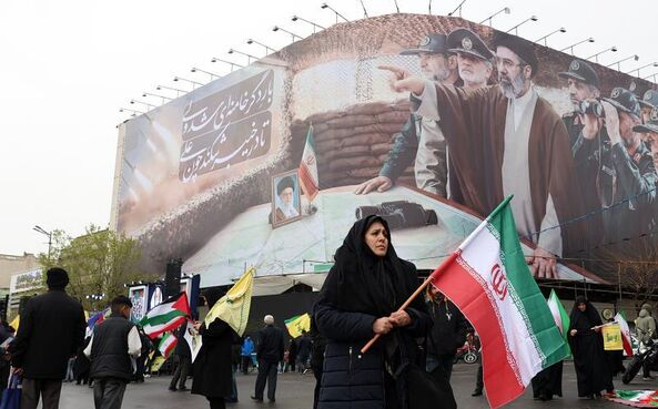 Uma mulher passa em frente de um cartaz com o novo líder supremo do Irão.