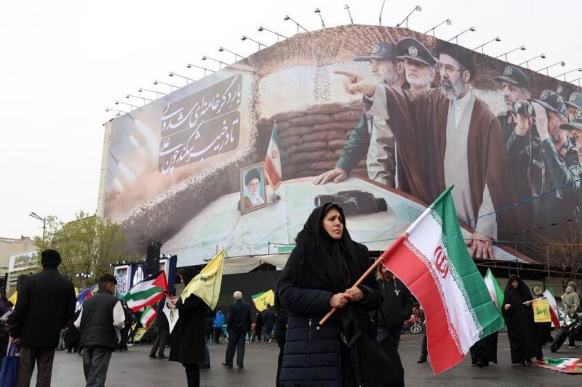 Uma mulher passa em frente de um cartaz com o novo líder supremo do Irão.