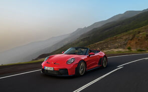 Um Porsche vermelho descapotável numa estrada panorâmica com montanhas