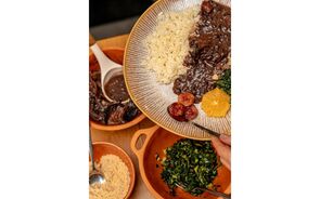 Prato de feijoada com arroz, laranja, couve e farofa