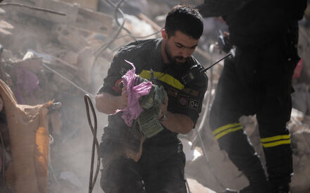 Um elemento das equipas de resgate retira dinheiro dos destroços de um edifício em Beirute atingido pela ofensiva israelita.