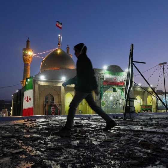 Jovem passa por complexo religioso que foi atingido por mísseis no Irão.