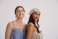 Mulheres sorrindo com vestidos bordados e touca de crochê