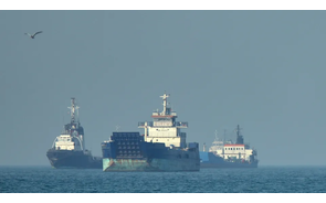 Embarcações navegam em mar calmo sob céu claro.
