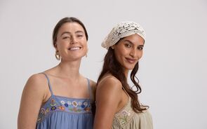 Mulheres sorrindo com vestidos bordados e touca de crochê