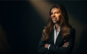 Retrato de mulher de fato e camisa branca, com os braços cruzados