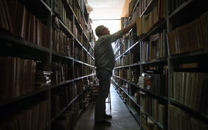 Homem escolhe um livro numa biblioteca antiga