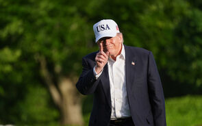 Trump com um boné escrito 'USA', aponta com o dedo