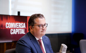 Homem de fato e gravata participa na Conversa Capital com microfone em estúdio