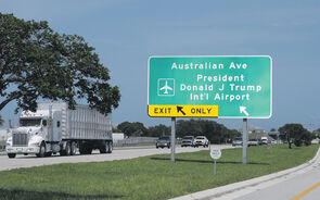Placa indica saída para o Aeroporto Internacional Donald J Trump